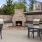 a fire pit with a grill and chairs in front of it