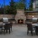 a patio with a fire pit and chairs and a brick wall